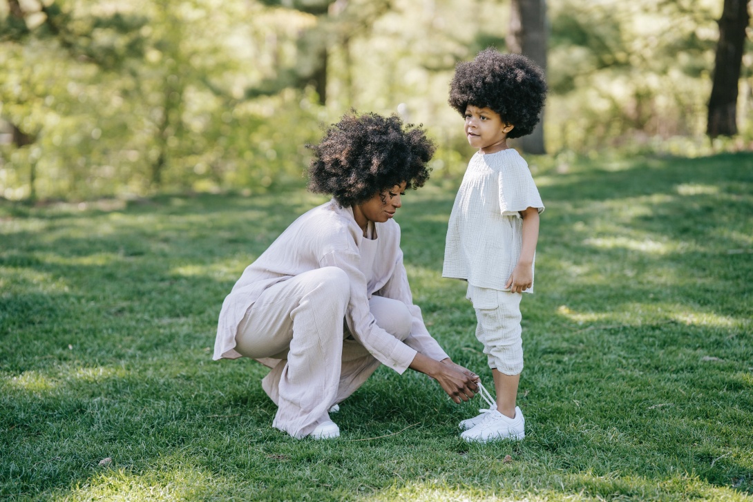 Mother kneels down to tie her daughter's shoes